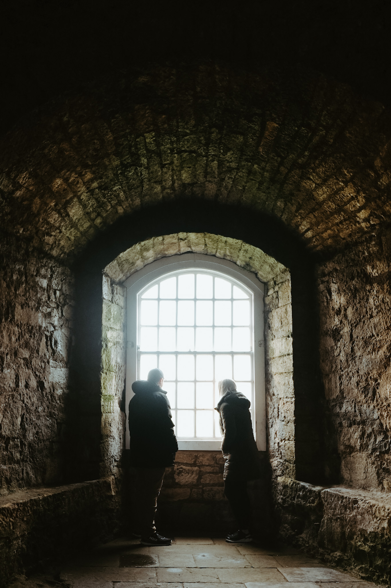 Couple looking out of large window in Blackness Castle in Scotland.