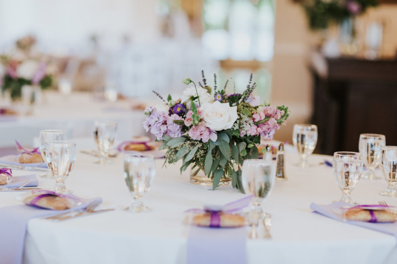 Guest Tables with lavender greenery and white compote centerpieces with lavender napkins an biscotti wedding favors