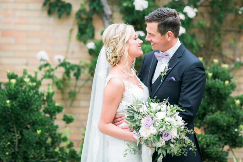Bride & Groom looking into each other's eyes with lavender and white bouquet and purple bowtie