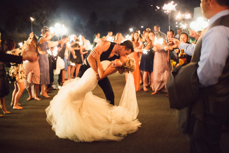 Groom dipping and kissing Bride during grand sparkler exit