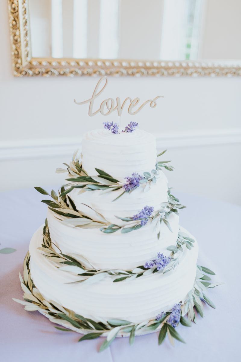 White buttercream wedding cake wrapped in olive branches and lavender with gold love cake topper 
