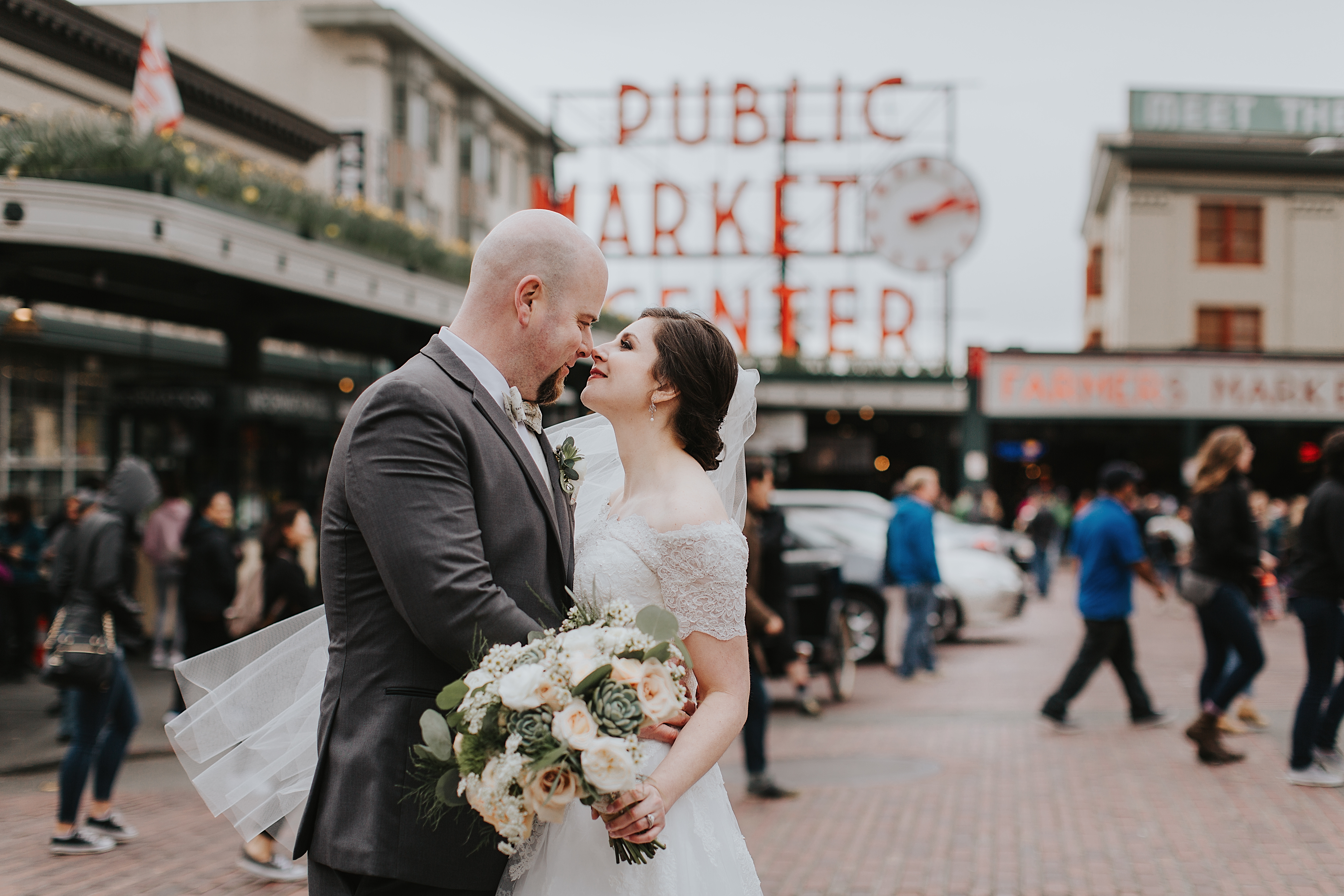 Bride and Groom with bouquet in front of Pike's Place Market in Seattle