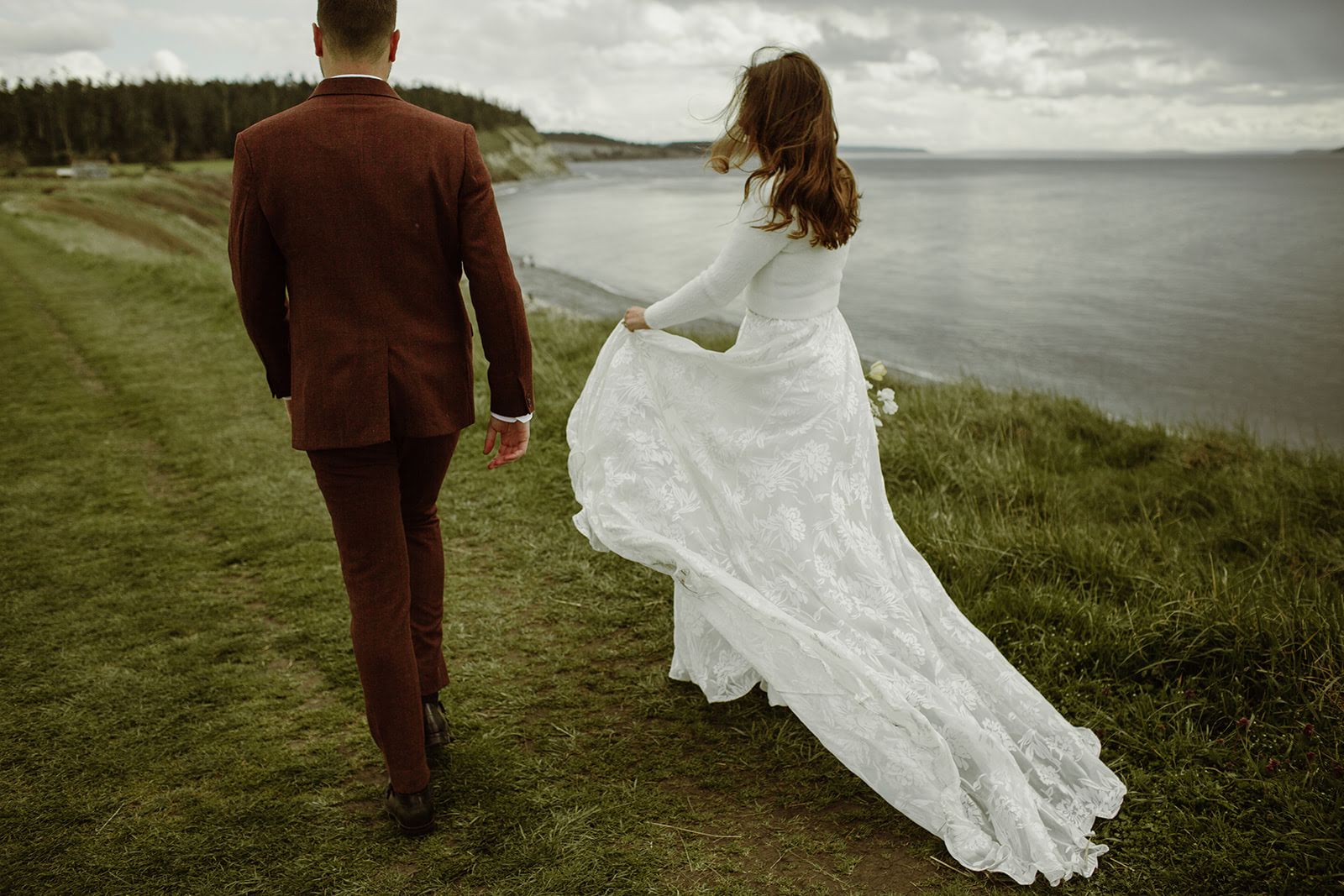 Bride and groom walking cliffside on Whidbey Island in Washington